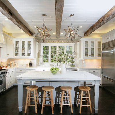 Kitchen - traditional u-shaped kitchen idea in San Francisco with glass-front cabinets, stainless steel appliances, marble countertops, white cabinets and white backsplash