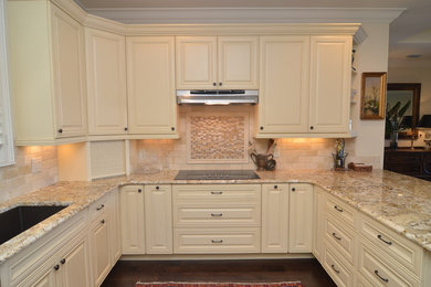 This is an example of a medium sized traditional u-shaped kitchen/diner in Orlando with a built-in sink, raised-panel cabinets, white cabinets, composite countertops, beige splashback, stone tiled splashback, stainless steel appliances, light hardwood flooring and an island.