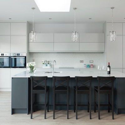 Example of a trendy light wood floor and beige floor kitchen design in Dublin with an undermount sink, flat-panel cabinets, gray cabinets, stainless steel appliances, an island and white countertops