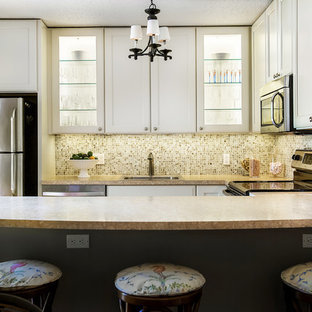 This is an example of a small tropical u-shaped eat-in kitchen in Miami with a drop-in sink, recessed-panel cabinets, white cabinets, laminate benchtops, multi-coloured splashback, mosaic tile splashback, stainless steel appliances, a peninsula and beige benchtop.