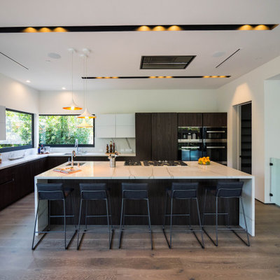 Inspiration for a large contemporary l-shaped medium tone wood floor and brown floor eat-in kitchen remodel in Los Angeles with an undermount sink, flat-panel cabinets, dark wood cabinets, quartz countertops, white backsplash, stone slab backsplash, paneled appliances, an island and white countertops