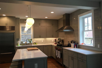 Imagen de cocina actual con salpicadero verde, salpicadero de azulejos tipo metro, electrodomésticos de acero inoxidable y una isla