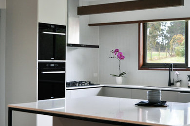 メルボルンにある中くらいなコンテンポラリースタイルのおしゃれなキッチン (ドロップインシンク、グレーのキャビネット、黒い調理設備、淡色無垢フローリング) の写真