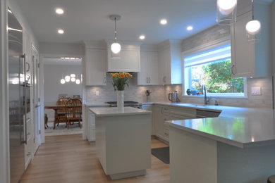 Inspiration for a large transitional u-shaped laminate floor and beige floor eat-in kitchen remodel in Vancouver with a farmhouse sink, shaker cabinets, white cabinets, quartz countertops, beige backsplash, ceramic backsplash, stainless steel appliances, an island and gray countertops