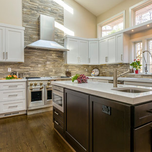Large transitional u-shaped kitchen pantry in DC Metro with an undermount sink, shaker cabinets, white cabinets, quartz benchtops, multi-coloured splashback, slate splashback, stainless steel appliances, medium hardwood floors and multiple islands.