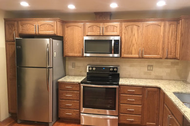 Example of a mid-sized classic l-shaped medium tone wood floor and brown floor eat-in kitchen design in Seattle with an undermount sink, recessed-panel cabinets, medium tone wood cabinets, granite countertops, white backsplash, marble backsplash, stainless steel appliances and multicolored countertops
