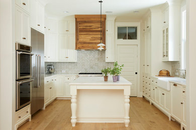 Foto på ett vintage u-kök, med en rustik diskho, vita skåp, marmorbänkskiva, stänkskydd i keramik, rostfria vitvaror, ljust trägolv, en köksö och skåp i shakerstil