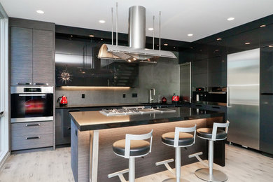 Example of a large minimalist l-shaped light wood floor eat-in kitchen design in Vancouver with an undermount sink, flat-panel cabinets, quartz countertops, gray backsplash, ceramic backsplash, stainless steel appliances, an island and gray cabinets