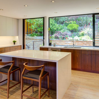 Inspiration for a small contemporary u-shaped light wood floor and beige floor kitchen remodel in San Francisco with flat-panel cabinets, medium tone wood cabinets, quartz countertops, white backsplash, stainless steel appliances, an island, white countertops and an undermount sink