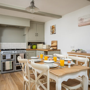 Inspiration for a medium sized traditional u-shaped kitchen/diner in Gloucestershire with a belfast sink, grey cabinets, wood worktops, stainless steel appliances, brown worktops, shaker cabinets, white splashback, metro tiled splashback, medium hardwood flooring, no island, brown floors and exposed beams.
