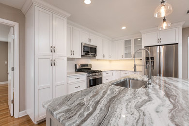 Open concept kitchen - mid-sized transitional l-shaped medium tone wood floor open concept kitchen idea in Other with an undermount sink, shaker cabinets, white cabinets, granite countertops, white backsplash, subway tile backsplash, stainless steel appliances and an island