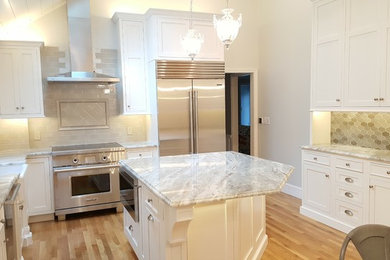 Inspiration for a large traditional kitchen in Boston with a belfast sink, shaker cabinets, white cabinets, granite worktops, multi-coloured splashback, glass tiled splashback, stainless steel appliances, light hardwood flooring, an island and brown floors.