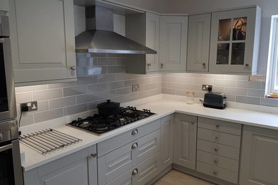 Cette image montre une cuisine design en U de taille moyenne avec des portes de placard grises, un sol en carrelage de céramique, îlot et un sol gris.