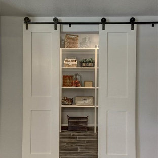 Large country l-shaped kitchen pantry in Phoenix with shaker cabinets, white cabinets, porcelain floors, granite benchtops, with island, black splashback, stone slab splashback, stainless steel appliances and a double-bowl sink.