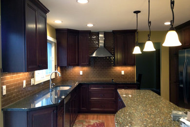 Enclosed kitchen - mid-sized traditional l-shaped medium tone wood floor enclosed kitchen idea in Detroit with a double-bowl sink, recessed-panel cabinets, dark wood cabinets, recycled glass countertops, beige backsplash, subway tile backsplash, stainless steel appliances and an island