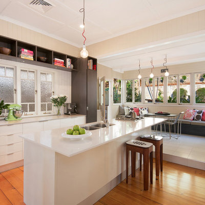 Inspiration for a contemporary galley medium tone wood floor eat-in kitchen remodel in Brisbane with a double-bowl sink, flat-panel cabinets, white cabinets, stainless steel appliances and an island