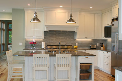 Example of a large transitional light wood floor kitchen design in Minneapolis with a farmhouse sink, shaker cabinets, white cabinets, granite countertops, green backsplash, glass tile backsplash, stainless steel appliances and an island