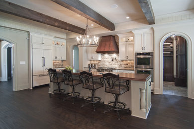 Example of a large classic galley dark wood floor and brown floor eat-in kitchen design in Charlotte with recessed-panel cabinets, white cabinets, wood countertops, beige backsplash, brick backsplash, paneled appliances and an island
