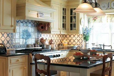 Example of a mid-sized classic u-shaped eat-in kitchen design in New York with an undermount sink, raised-panel cabinets, beige cabinets, granite countertops, multicolored backsplash, ceramic backsplash, stainless steel appliances, an island and black countertops