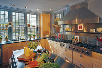 Imagen de cocina clásica renovada con fregadero de doble seno, puertas de armario de madera clara, salpicadero verde, electrodomésticos de acero inoxidable y una isla