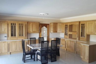 This is an example of a large traditional kitchen in Other with raised-panel cabinets, light wood cabinets, integrated appliances and porcelain flooring.
