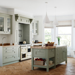 This is an example of a traditional single-wall kitchen/diner in Manchester with a submerged sink, shaker cabinets, green cabinets, wood worktops, green splashback, integrated appliances, medium hardwood flooring, an island, brown floors and brown worktops.