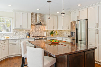 Example of a transitional u-shaped medium tone wood floor and brown floor kitchen design in San Diego with recessed-panel cabinets, white cabinets, multicolored backsplash, stainless steel appliances and an island