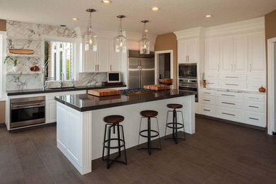 Large transitional dark wood floor kitchen photo in Other with a drop-in sink, raised-panel cabinets, white cabinets, quartzite countertops, stone slab backsplash, stainless steel appliances and an island