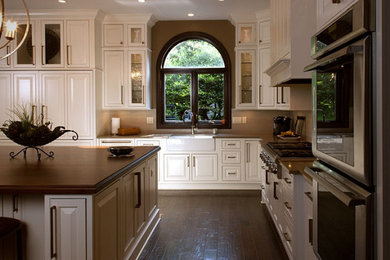 Eat-in kitchen - large l-shaped dark wood floor eat-in kitchen idea in Miami with a farmhouse sink, beaded inset cabinets, white cabinets, solid surface countertops, beige backsplash, stainless steel appliances and an island