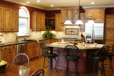 Küche in L-Form mit Kassettenfronten, hellbraunen Holzschränken, Küchengeräten aus Edelstahl, braunem Holzboden und Kücheninsel in Atlanta