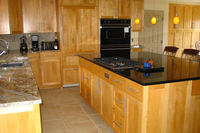 Eat-in kitchen - mid-sized l-shaped ceramic tile eat-in kitchen idea in Milwaukee with a drop-in sink, recessed-panel cabinets, light wood cabinets, granite countertops, black appliances and an island