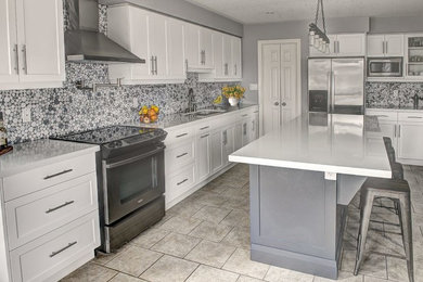 Example of a large trendy l-shaped ceramic tile and beige floor kitchen design in Vancouver with an undermount sink, shaker cabinets, white cabinets, quartz countertops, gray backsplash, stainless steel appliances, an island and white countertops