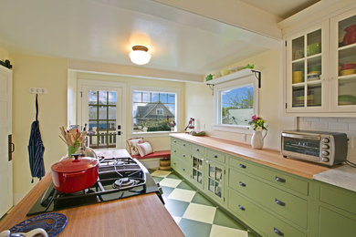 Inspiration for a craftsman u-shaped painted wood floor enclosed kitchen remodel in Seattle with glass-front cabinets, green cabinets, wood countertops, white backsplash, subway tile backsplash, stainless steel appliances and an island