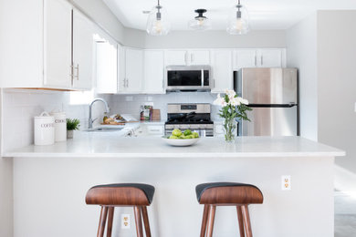 Example of a small minimalist u-shaped porcelain tile and gray floor eat-in kitchen design in New York with a double-bowl sink, recessed-panel cabinets, white cabinets, quartz countertops, white backsplash, subway tile backsplash, stainless steel appliances, a peninsula and white countertops