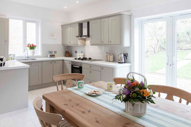 Inspiration for a medium sized traditional u-shaped kitchen/diner in Kent with recessed-panel cabinets, grey cabinets, recycled glass countertops and white splashback.