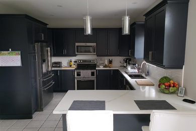 Example of a mid-sized trendy u-shaped eat-in kitchen design in Ottawa with a double-bowl sink, recessed-panel cabinets, blue cabinets, quartz countertops, white backsplash, stainless steel appliances, a peninsula and white countertops