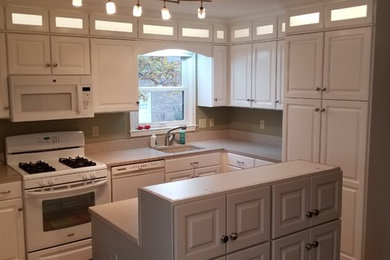 Example of a mid-sized classic l-shaped medium tone wood floor and brown floor eat-in kitchen design in Louisville with an undermount sink, raised-panel cabinets, white cabinets, green backsplash, white appliances, an island and laminate countertops