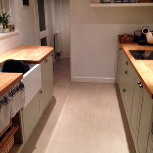 Design ideas for an expansive contemporary u-shaped eat-in kitchen in Devon with an undermount sink, louvered cabinets, beige cabinets, wood benchtops, white splashback, ceramic splashback, stainless steel appliances, vinyl floors and a peninsula.