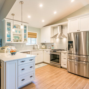 Design ideas for a mid-sized beach style u-shaped eat-in kitchen in Sacramento with an undermount sink, glass-front cabinets, white cabinets, marble benchtops, white splashback, glass tile splashback, stainless steel appliances, ceramic floors and a peninsula.