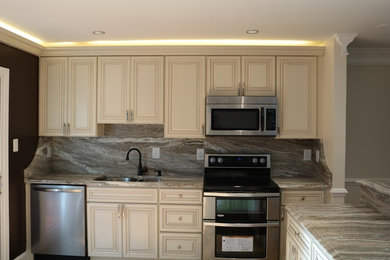 Kitchen - mid-sized transitional l-shaped kitchen idea in DC Metro with an undermount sink, raised-panel cabinets, white cabinets, granite countertops, gray backsplash, stainless steel appliances and an island