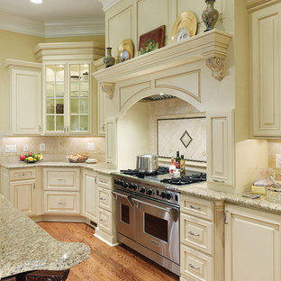Idee per un grande cucina con isola centrale classico con ante con bugna sagomata, ante bianche, top in granito, paraspruzzi beige, paraspruzzi con piastrelle in pietra, elettrodomestici da incasso, pavimento in legno massello medio e pavimento marrone