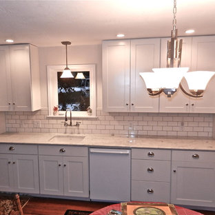 Example of an arts and crafts single-wall medium tone wood floor eat-in kitchen design in Seattle with an undermount sink, shaker cabinets, white cabinets, marble countertops, white backsplash, subway tile backsplash and white appliances