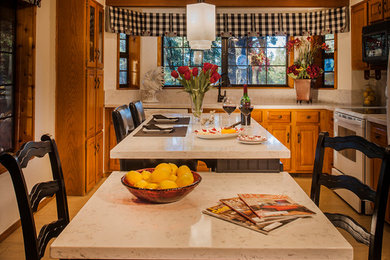 フェニックスにある中くらいなトラディショナルスタイルのおしゃれなキッチン (アンダーカウンターシンク、レイズドパネル扉のキャビネット、中間色木目調キャビネット、クオーツストーンカウンター、白いキッチンパネル、石スラブのキッチンパネル、白い調理設備、磁器タイルの床、ベージュの床、白いキッチンカウンター) の写真