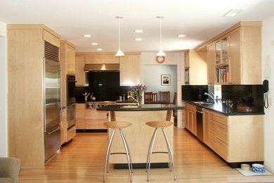Mid-sized trendy u-shaped light wood floor eat-in kitchen photo in Los Angeles with a double-bowl sink, shaker cabinets, light wood cabinets, granite countertops, black backsplash, stainless steel appliances and an island
