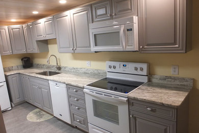 Example of a mid-sized trendy galley porcelain tile eat-in kitchen design in Tampa with a single-bowl sink, raised-panel cabinets, gray cabinets, marble countertops, white appliances and a peninsula