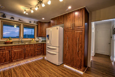 Mid-sized transitional l-shaped dark wood floor enclosed kitchen photo in Hawaii with an undermount sink, raised-panel cabinets, dark wood cabinets, quartz countertops, white backsplash, glass tile backsplash, white appliances and no island