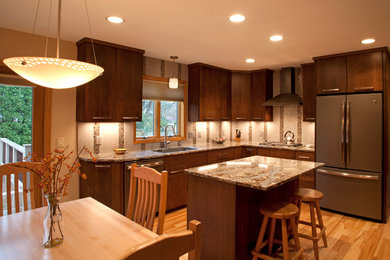 Eat-in kitchen - mid-sized contemporary u-shaped medium tone wood floor eat-in kitchen idea in Other with an undermount sink, flat-panel cabinets, brown cabinets, quartz countertops, multicolored backsplash, glass tile backsplash, stainless steel appliances and an island