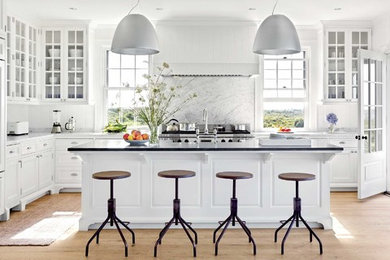 Inspiration for a mid-sized transitional l-shaped light wood floor and black floor enclosed kitchen remodel in Chicago with a farmhouse sink, shaker cabinets, white cabinets, white backsplash, stainless steel appliances, an island, marble countertops and marble backsplash