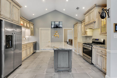 Inspiration for a mid-sized timeless galley porcelain tile and gray floor eat-in kitchen remodel in New Orleans with an undermount sink, raised-panel cabinets, distressed cabinets, granite countertops, gray backsplash, porcelain backsplash, stainless steel appliances, an island and multicolored countertops