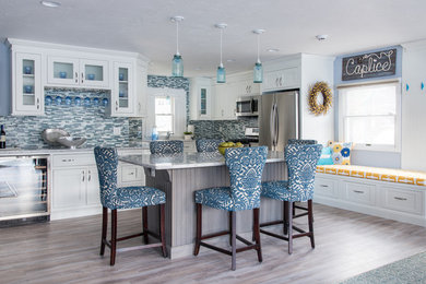 Mid-sized transitional light wood floor eat-in kitchen photo in Boston with an undermount sink, shaker cabinets, white cabinets, marble countertops, blue backsplash, matchstick tile backsplash, stainless steel appliances and an island